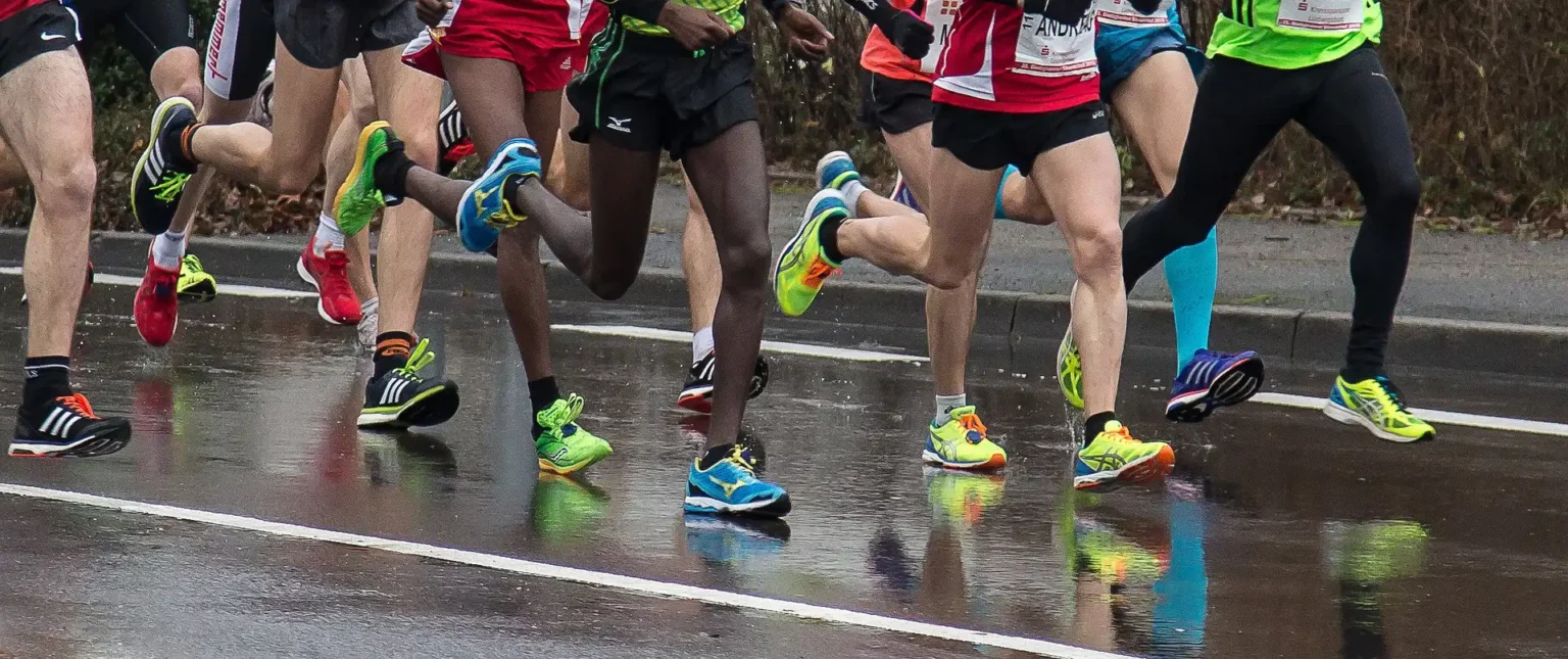 In the picture we can see the legs of a lot of people in sportwear running.