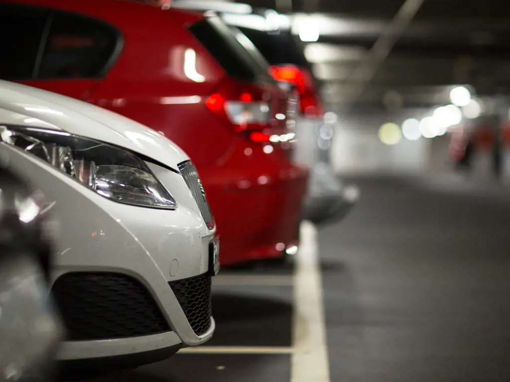 Nell'immagine si vede una fila di auto parcheggiate in un garage coperto.